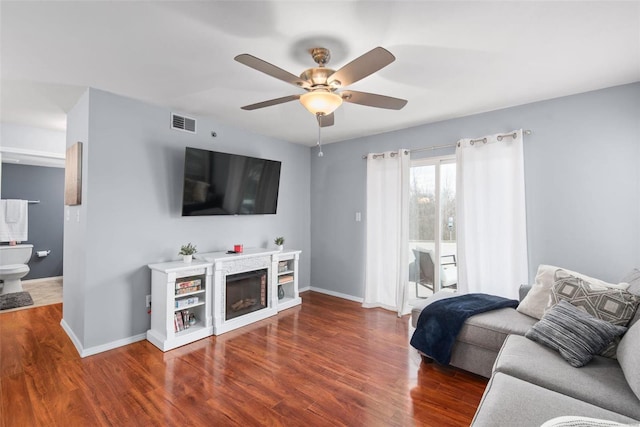 living room featuring ceiling fan and dark hardwood / wood-style flooring