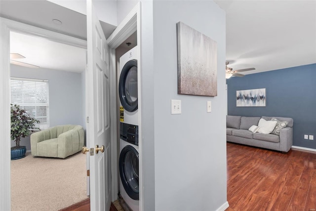 laundry area featuring dark wood-type flooring, ceiling fan, and stacked washer / drying machine