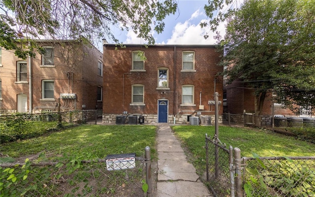 view of front of home featuring fence private yard, central air condition unit, brick siding, and a front yard