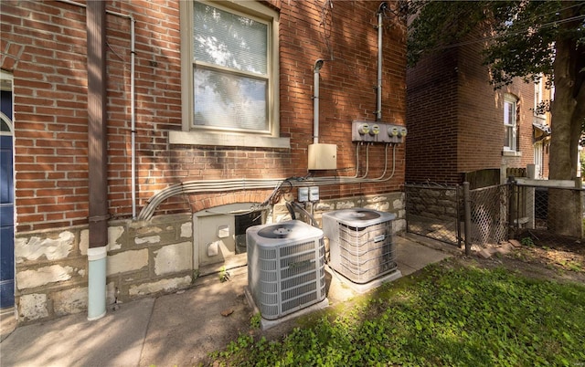 details featuring electric meter, brick siding, and central AC unit