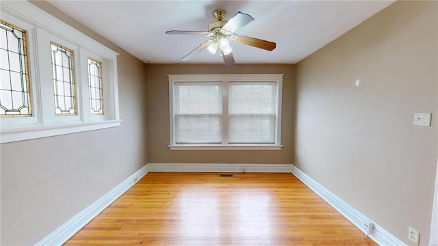 spare room featuring a ceiling fan, light wood-style flooring, and baseboards