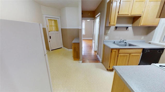 kitchen with dishwasher, freestanding refrigerator, light countertops, light floors, and a sink