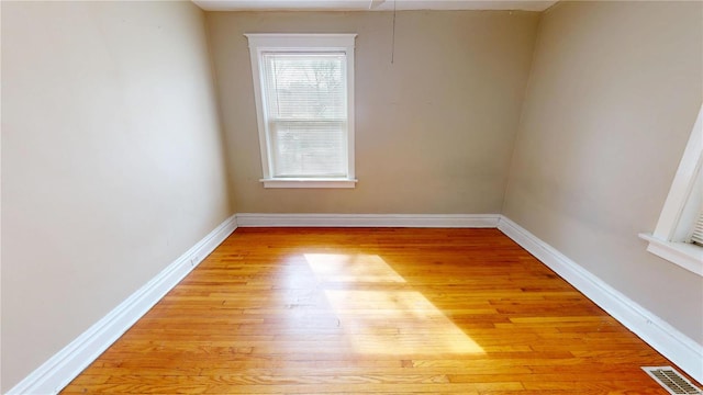 empty room with light wood-type flooring, visible vents, and baseboards