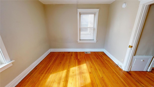 empty room featuring baseboards, visible vents, and wood finished floors