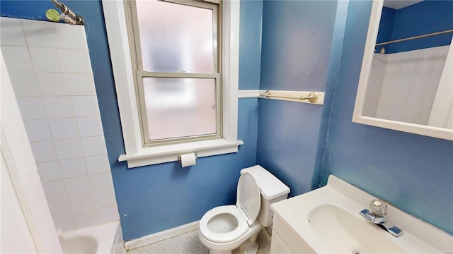 bathroom with tub / shower combination, a sink, toilet, and baseboards