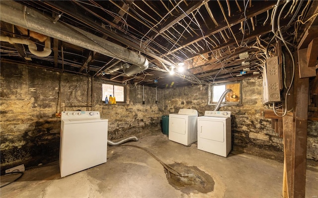 below grade area featuring water heater, plenty of natural light, and washer and clothes dryer