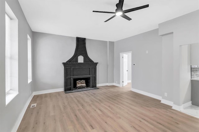 unfurnished living room with light wood-style floors, visible vents, a fireplace, and baseboards