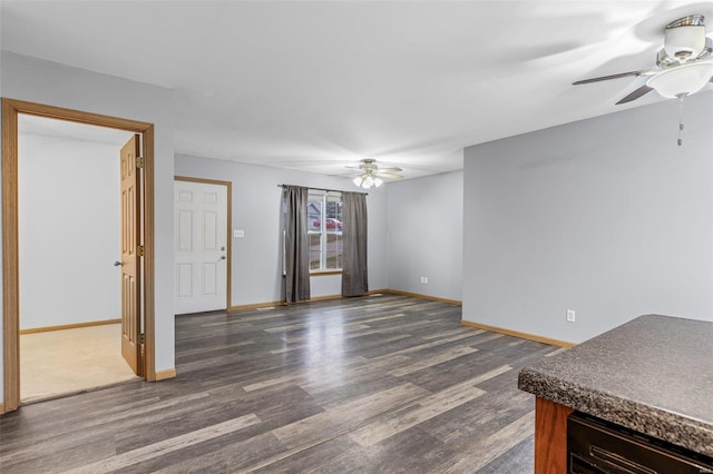 unfurnished living room featuring dark wood-type flooring and ceiling fan