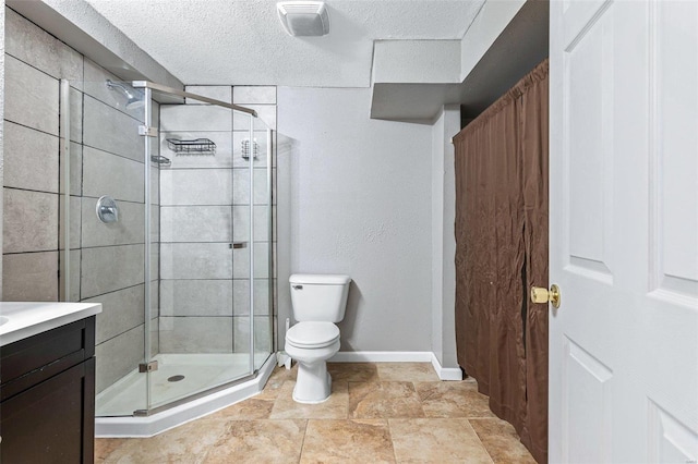 bathroom with a shower with door, vanity, a textured ceiling, and toilet