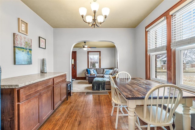 dining area featuring dark hardwood / wood-style flooring and ceiling fan with notable chandelier