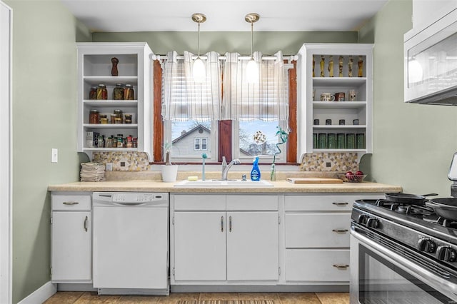 kitchen featuring white appliances, sink, hanging light fixtures, and white cabinets