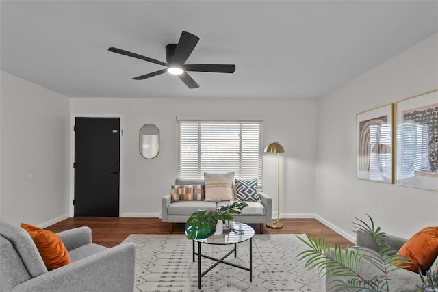 living area featuring wood finished floors, a ceiling fan, and baseboards