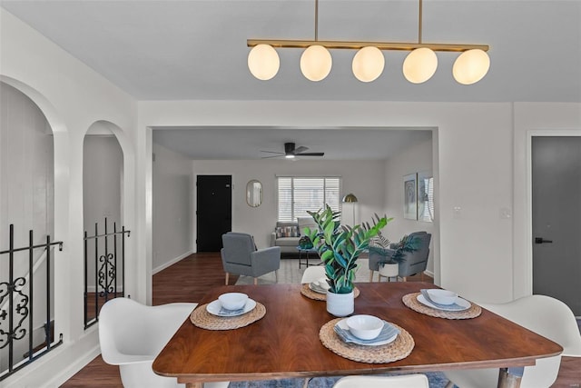 dining space featuring dark wood-style floors, arched walkways, and ceiling fan