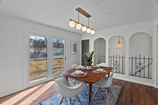 dining room with arched walkways, wood finished floors, and baseboards