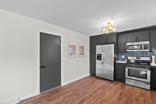 kitchen with dark wood-style floors, light countertops, visible vents, decorative backsplash, and appliances with stainless steel finishes