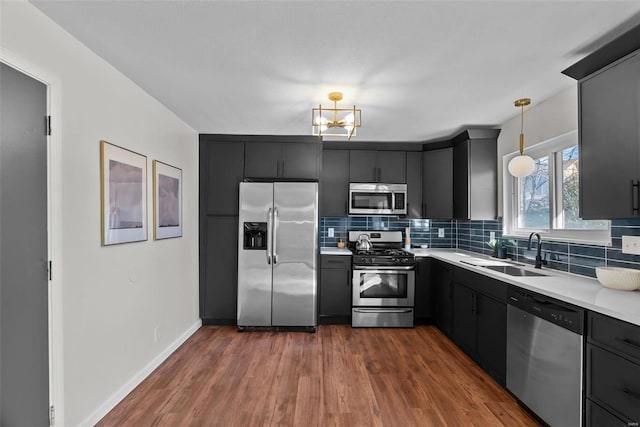 kitchen featuring dark wood-style floors, stainless steel appliances, light countertops, decorative backsplash, and a sink