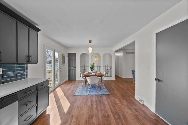 dining area featuring baseboards, visible vents, arched walkways, and wood finished floors