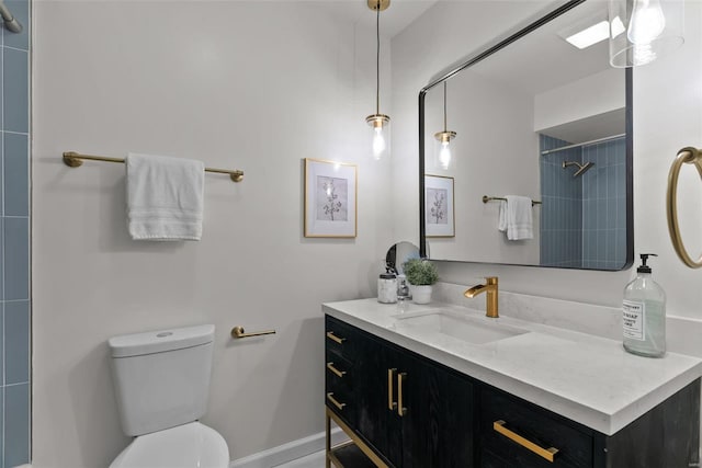 bathroom featuring baseboards, a tile shower, vanity, and toilet