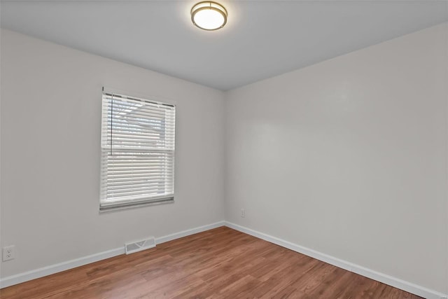 empty room with visible vents, baseboards, and wood finished floors