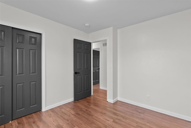 unfurnished bedroom with light wood-type flooring, visible vents, and baseboards