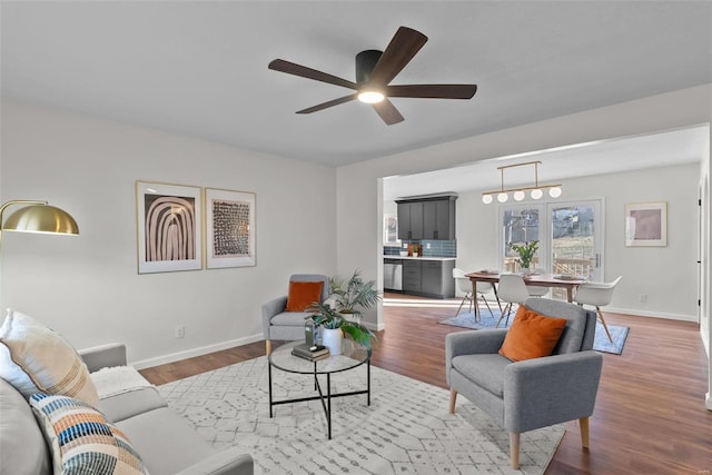 living area featuring ceiling fan, baseboards, and wood finished floors