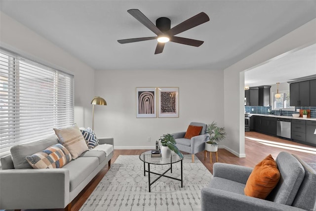 living room featuring light wood-type flooring, ceiling fan, and baseboards