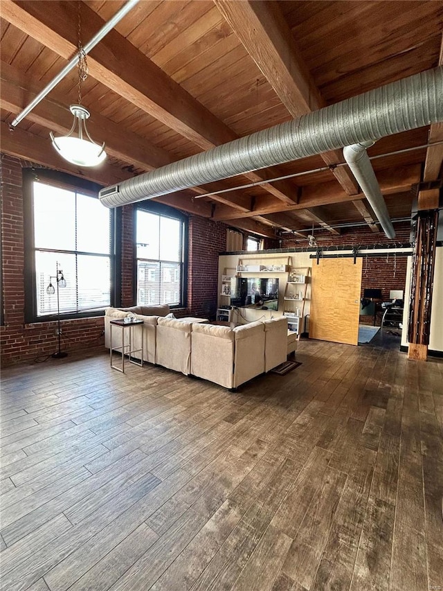 unfurnished living room featuring beam ceiling, wood ceiling, wood-type flooring, brick wall, and a barn door