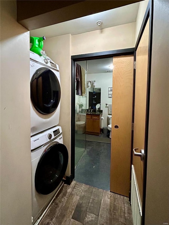 washroom with dark hardwood / wood-style flooring and stacked washer and clothes dryer