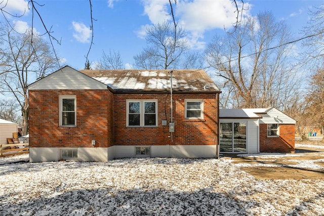 view of snowy exterior featuring brick siding