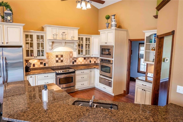 kitchen featuring sink, premium range hood, appliances with stainless steel finishes, high vaulted ceiling, and white cabinets