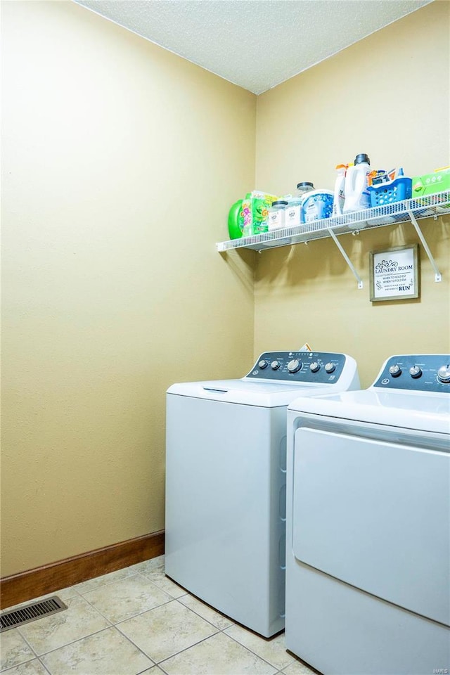 laundry area with light tile patterned floors, washing machine and dryer, and a textured ceiling