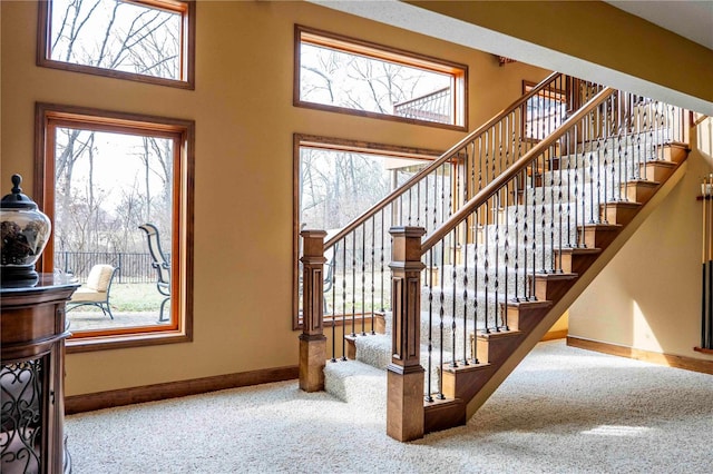 stairs with a towering ceiling, plenty of natural light, and carpet flooring