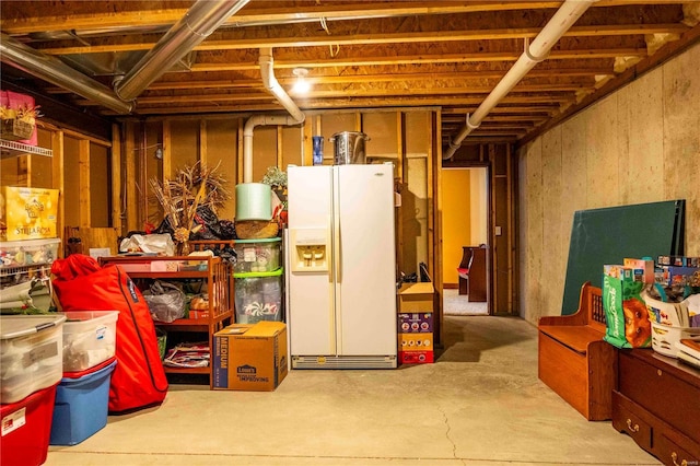 basement featuring white refrigerator with ice dispenser