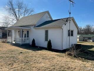 back of property with covered porch and a lawn