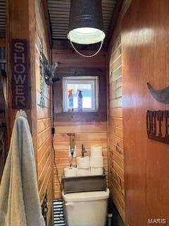 bathroom with toilet and wood walls