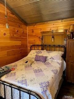 bedroom featuring lofted ceiling and wood walls