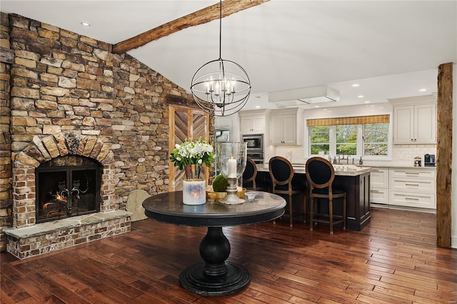 interior space with vaulted ceiling with beams, recessed lighting, a notable chandelier, a fireplace, and dark wood-style floors