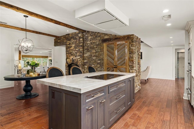 kitchen featuring visible vents, dark wood finished floors, a center island, hanging light fixtures, and black electric stovetop