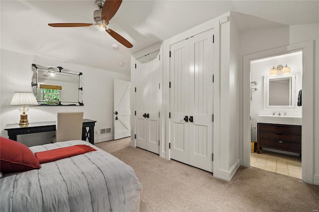 bedroom featuring visible vents, a ceiling fan, light carpet, connected bathroom, and vaulted ceiling