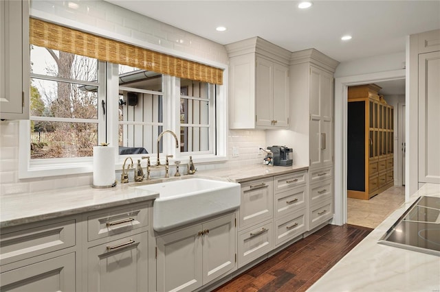 kitchen featuring dark wood finished floors, light stone counters, a sink, and white cabinetry