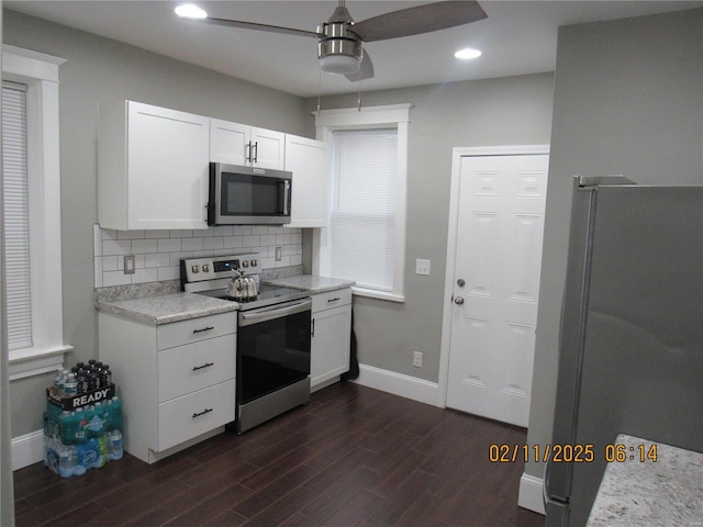 kitchen with ceiling fan, appliances with stainless steel finishes, white cabinetry, dark hardwood / wood-style floors, and decorative backsplash