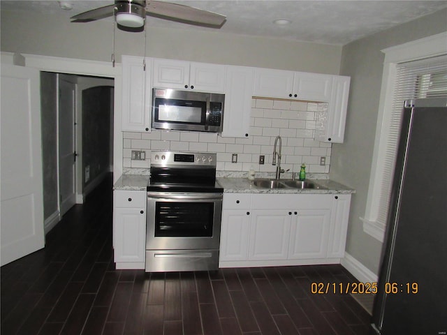 kitchen featuring dark wood-type flooring, sink, white cabinetry, appliances with stainless steel finishes, and backsplash