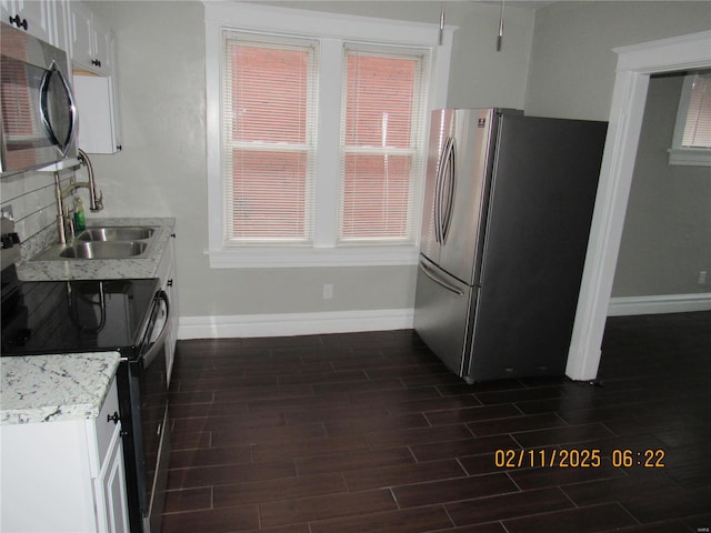 kitchen with white cabinetry, appliances with stainless steel finishes, sink, and light stone counters