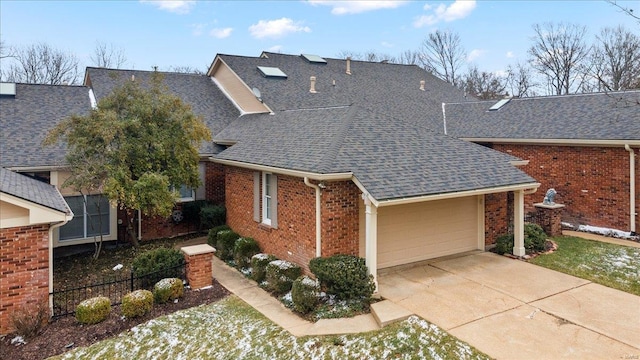 view of front of property with brick siding, fence, roof with shingles, driveway, and an attached garage