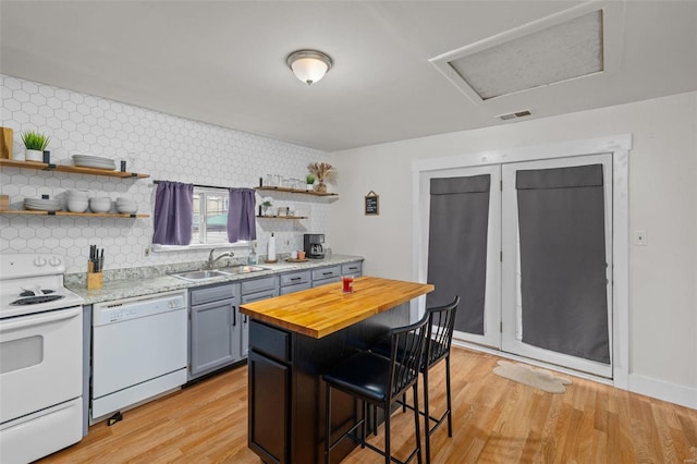 kitchen with white appliances, a breakfast bar, sink, and light hardwood / wood-style flooring