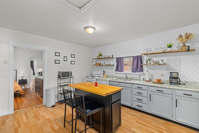 kitchen featuring sink, a breakfast bar area, a center island, white appliances, and light hardwood / wood-style flooring