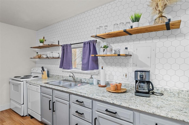 kitchen with sink, tasteful backsplash, light stone counters, white appliances, and light hardwood / wood-style floors