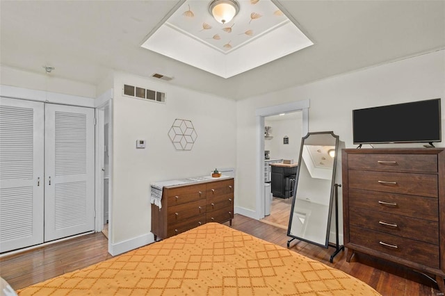 bedroom with wood-type flooring, ensuite bathroom, and a closet