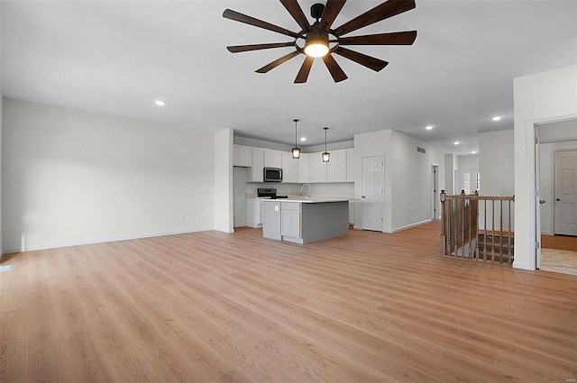 unfurnished living room with ceiling fan and light wood-type flooring