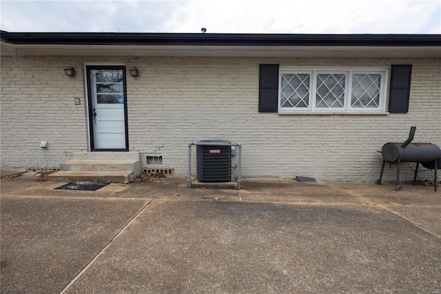 view of exterior entry featuring crawl space, central AC unit, and brick siding